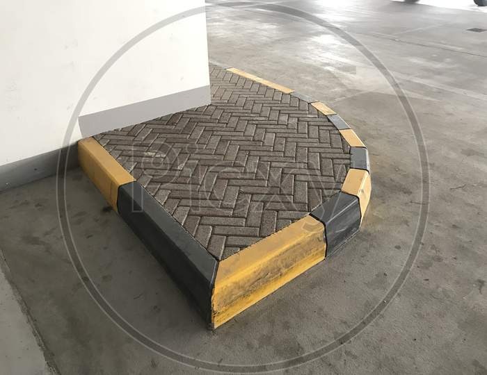 Interlock Tile Bricks And Protected By Concrete Kerb Stones Painted By Yellow And Black Color In An Finished Vehicle Parking Basement Of An High Rise Building