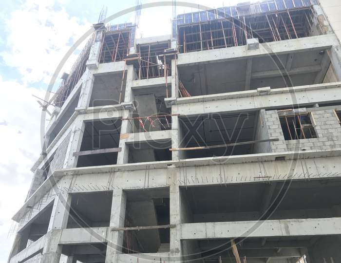 An Ongoing Construction Site Front Elevation View Of Skeleton Or Framed Structure Consists Of Columns Slab Beams And Shuttering Work For Slab In Progress And Workmen Are Working At Various Levels
