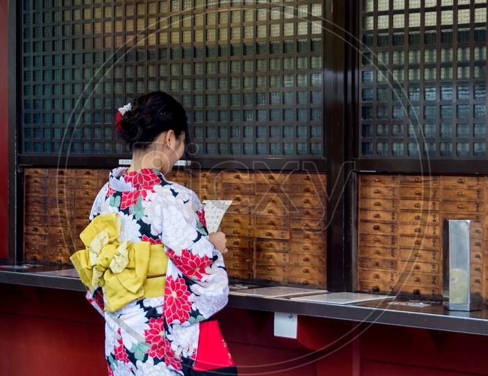 Girl In Kimono Reading Omikuji In Senso-Ji Buddhist Temple In Tokyo Japan