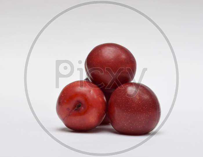 Raw Organic Red Plums On White Background, Red Maroon Shades, Fresh Shiny Fruits