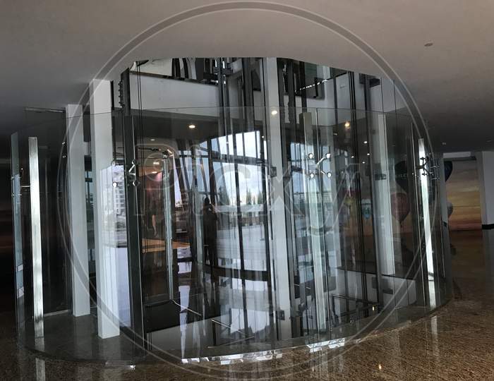 Passenger Lifts Or Elevators In Circular Shaped Covered By Toughened Glass Partition For Consumers Or User