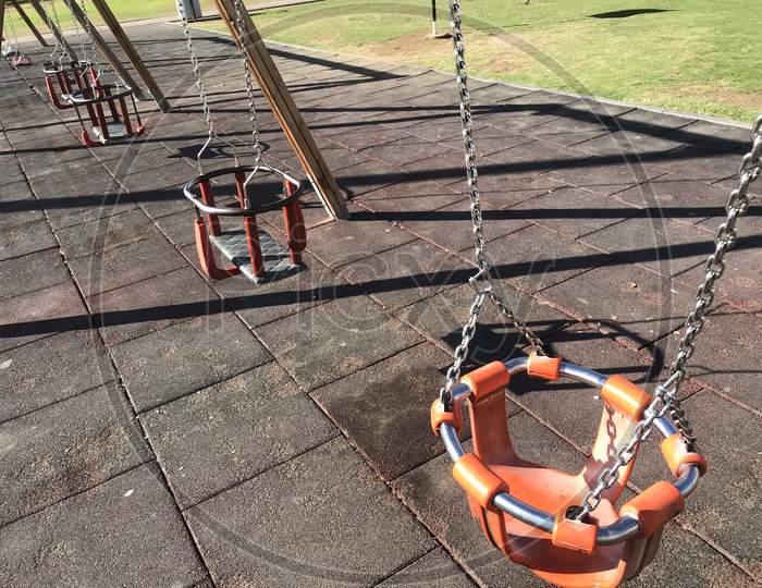 Orange Color Swing With Necessary Guard Ring For Children Playing In A Park For An Healthy Lifestyle In The Park Or Outdoor Area To Lead Healthy Life