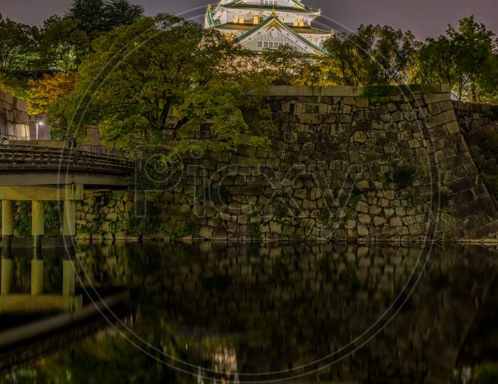 Night View Of Osaka Castle Reflecting In Water Moat In Osaka, Japan