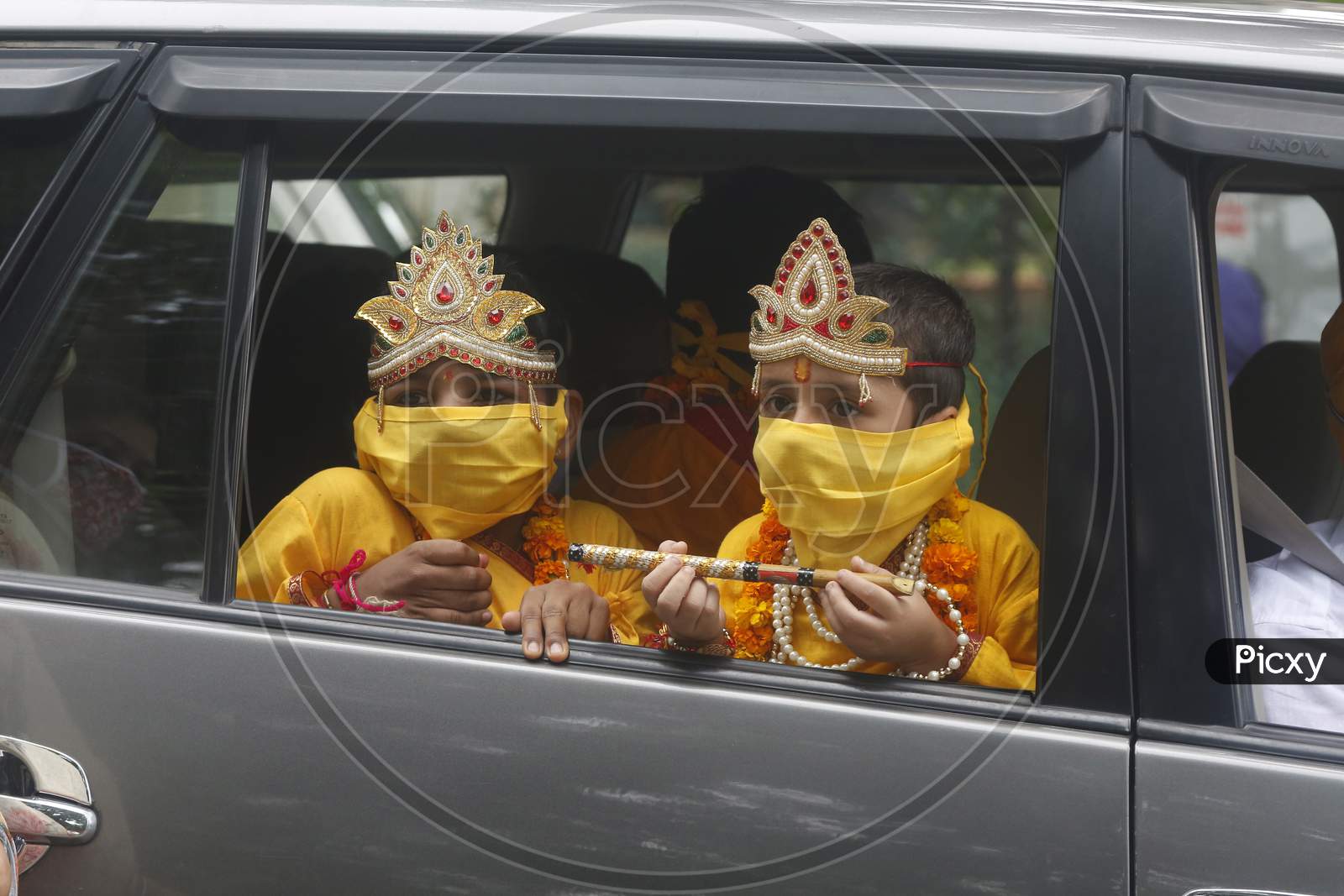 Children wear mask, dressed as Hindu Lord Krishna ride in a car during Janmashtami celebrations, in Chandigarh August 11, 2020
