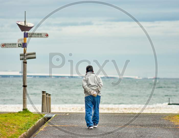 Old Japanese Man Walking Towards The Sea