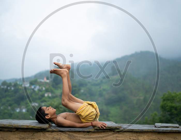 A Young Indian Cute Kid Doing Yoga In The Mountains,Wearing A Dhoti
