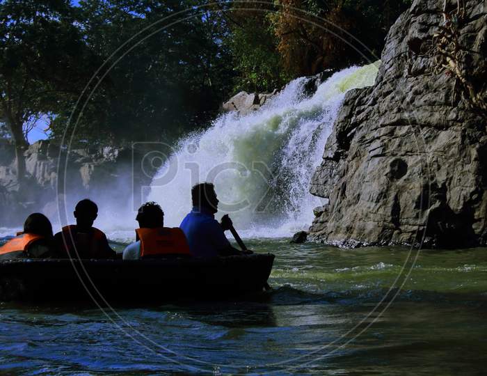 tourists are enjoying coracle ride on kaveri river in front of hogenakkal waterfalls. the beautiful waterfalls is located at the foothills of western ghats mountain range on the border between karnataka and tamilnadu, india