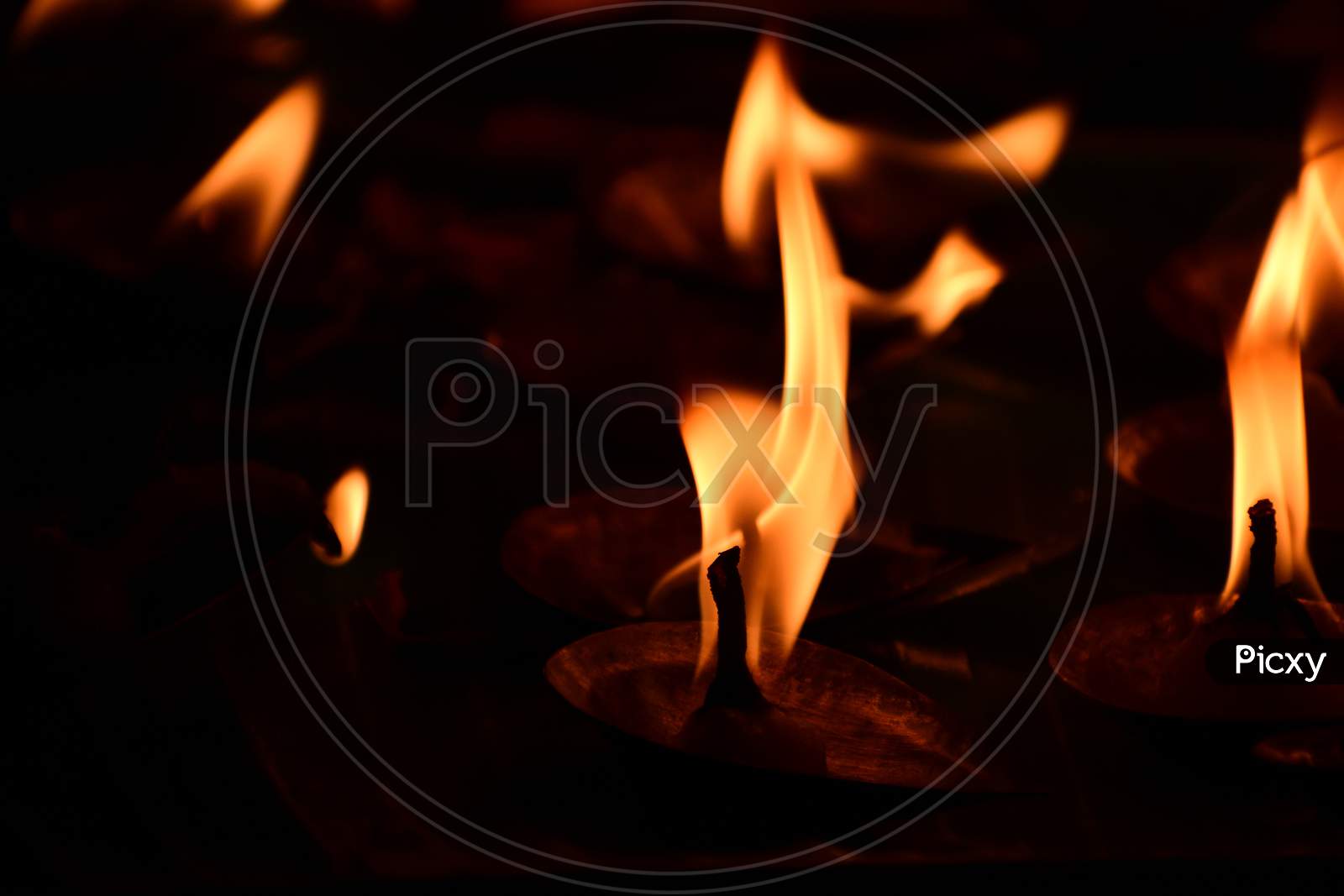Creative Photography Of Many Realistic Burning Oil Lamps, Candles In Diwali, An Indian Festival In Evening. Colorful Red, Yellow Orange Fire Flame Lit On Dark Night Background With Noise Grain Effect.