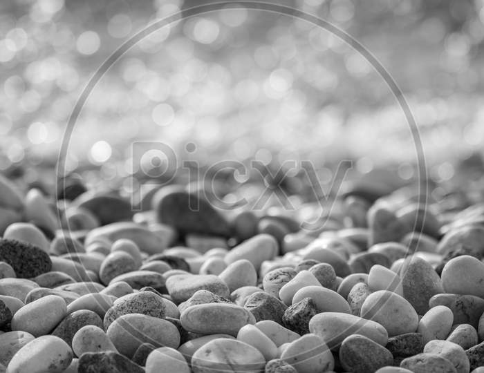 Pebbles On The Beach With The Blurry Bokeh Of A Coming Crashing Wave