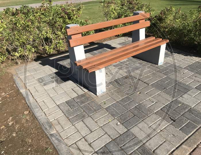 A Wooden Bench With Concrete Supports Built In Between The Interlock Floor Tile Flooring Isolated For A Healthy And Relax Conversation With Friend Or Family Relative In A Park Or Outdoor