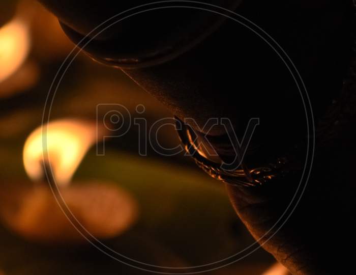 Creative Photography Of Many Realistic Burning Oil Lamps And Candles In A Festival In Evening. A Hand Is Lighting Colorful Red, Yellow, Fire Flame At Night On Dark Background With Noise, Grain Effect.