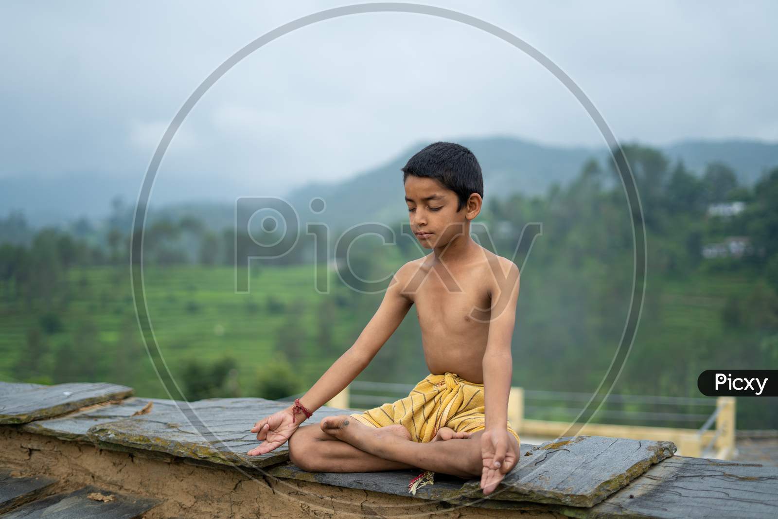 A Young Indian Cute Kid Doing Yoga In The Mountains,Wearing A Dhoti.