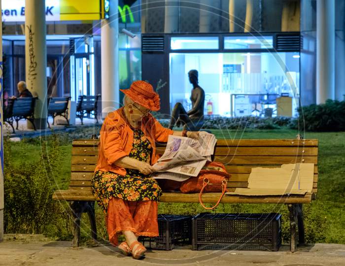 Elderly Lady Reading Newspapers In The Street In Belgrade, Capital Of Serbia