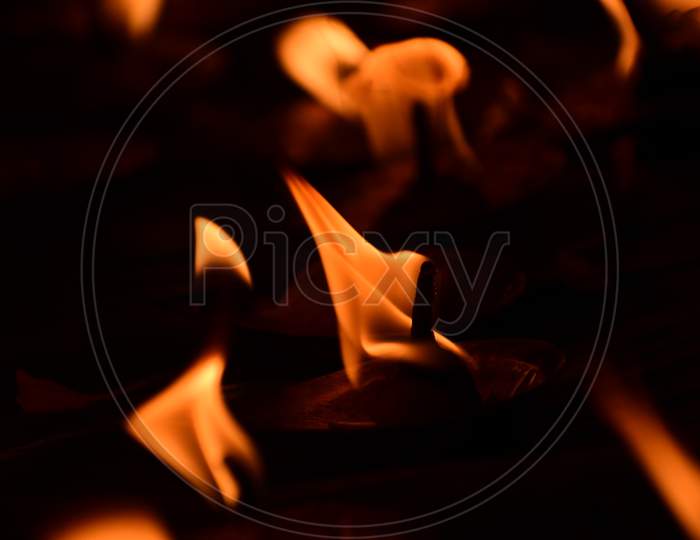 Creative Photography Of Many Realistic Burning Oil Lamps, Candles In Diwali, An Indian Festival In Evening. Colorful Red, Yellow Orange Fire Flame Lit On Dark Night Background With Noise Grain Effect.