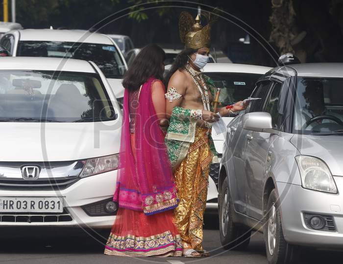 A man wears mask  dressed as Hindu Lord Krishna and a woman dressed his consort Radha, distribute  masks to people at a road during Janmashtami celebrations, in Chandigarh August 11, 2020