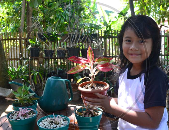 Little Girl Love Gardening Sit While Holding A Potted Plant