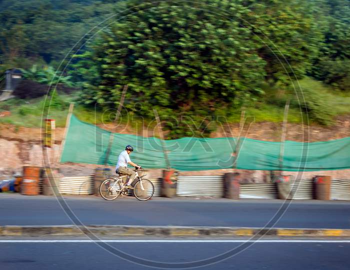 Pune, Maharashtra, India - October 4Th, 2017 : Motion Blur Image Of An Old Bicycle Rider Wearing Helmet For Safety .
