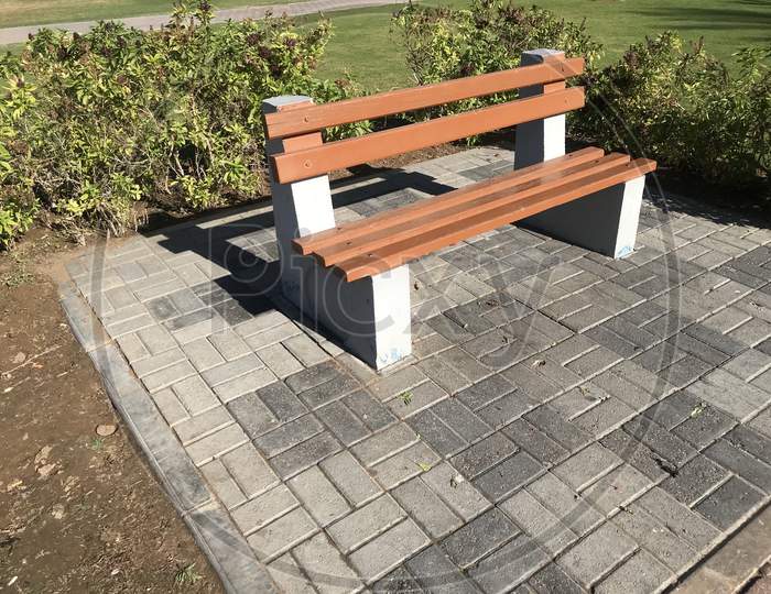A Wooden Bench With Concrete Supports Built In Between The Interlock Floor Tile Flooring Isolated For A Healthy And Relax Conversation With Friend Or Family Relative In A Park Or Outdoor
