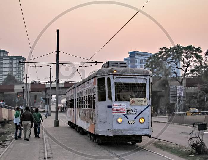 Kolkata, West Bengal, India-January 28Th,2012: Colorful Tram Moving Through Busy, Streets Of Kolkata On Background Of Beautiful Sunset..