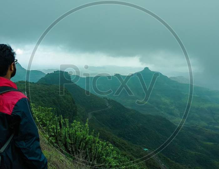 Side-Backward Photograph Of A Man Looking At A Distant Mountain Peak On A Trek In Purandar, Maharashtra, India