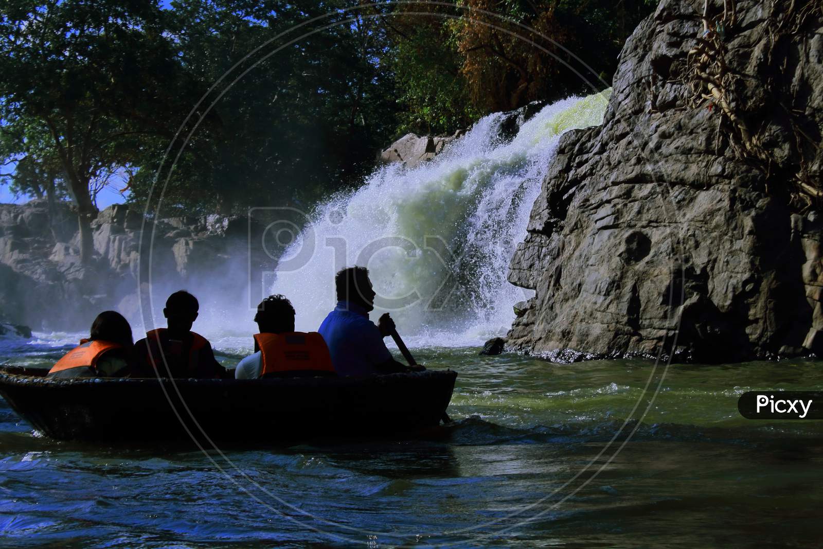 tourists are enjoying coracle ride on kaveri river in front of hogenakkal waterfalls. the beautiful waterfalls is located at the foothills of western ghats mountain range on the border between karnataka and tamilnadu, india