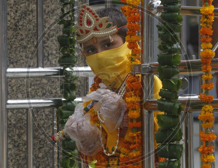 A boy wears mask and gloves, dressed as Hindu Lord Krishna arrive at a temple  during Janmashtami celebrations, in Chandigarh August 11, 2020