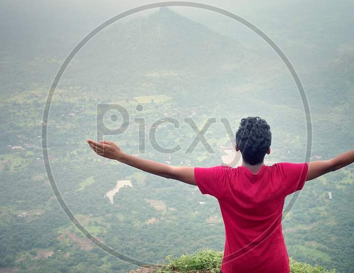 Young person standing  with raising his hands  in front of mountain for relaxing, freedom and wellness, enjoying natural view