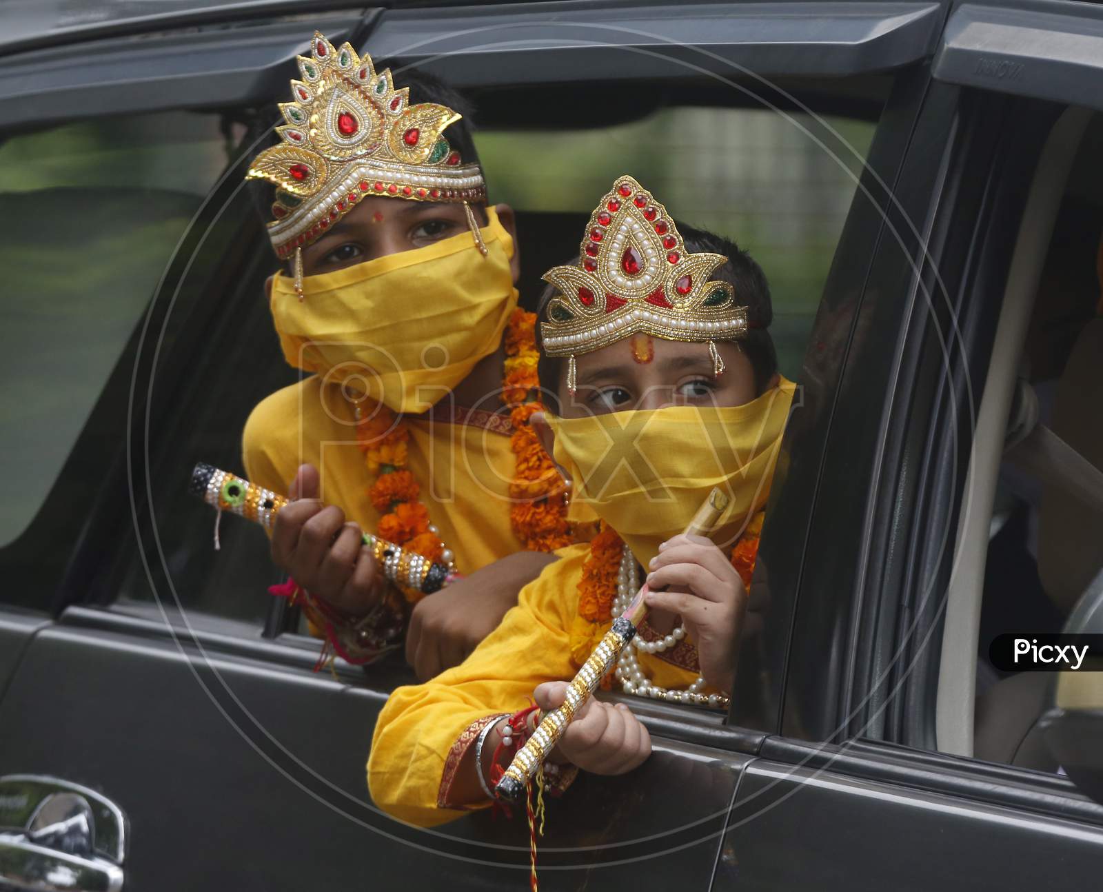 Children wear mask, dressed as Hindu Lord Krishna ride in a car during Janmashtami celebrations, in Chandigarh August 11, 2020