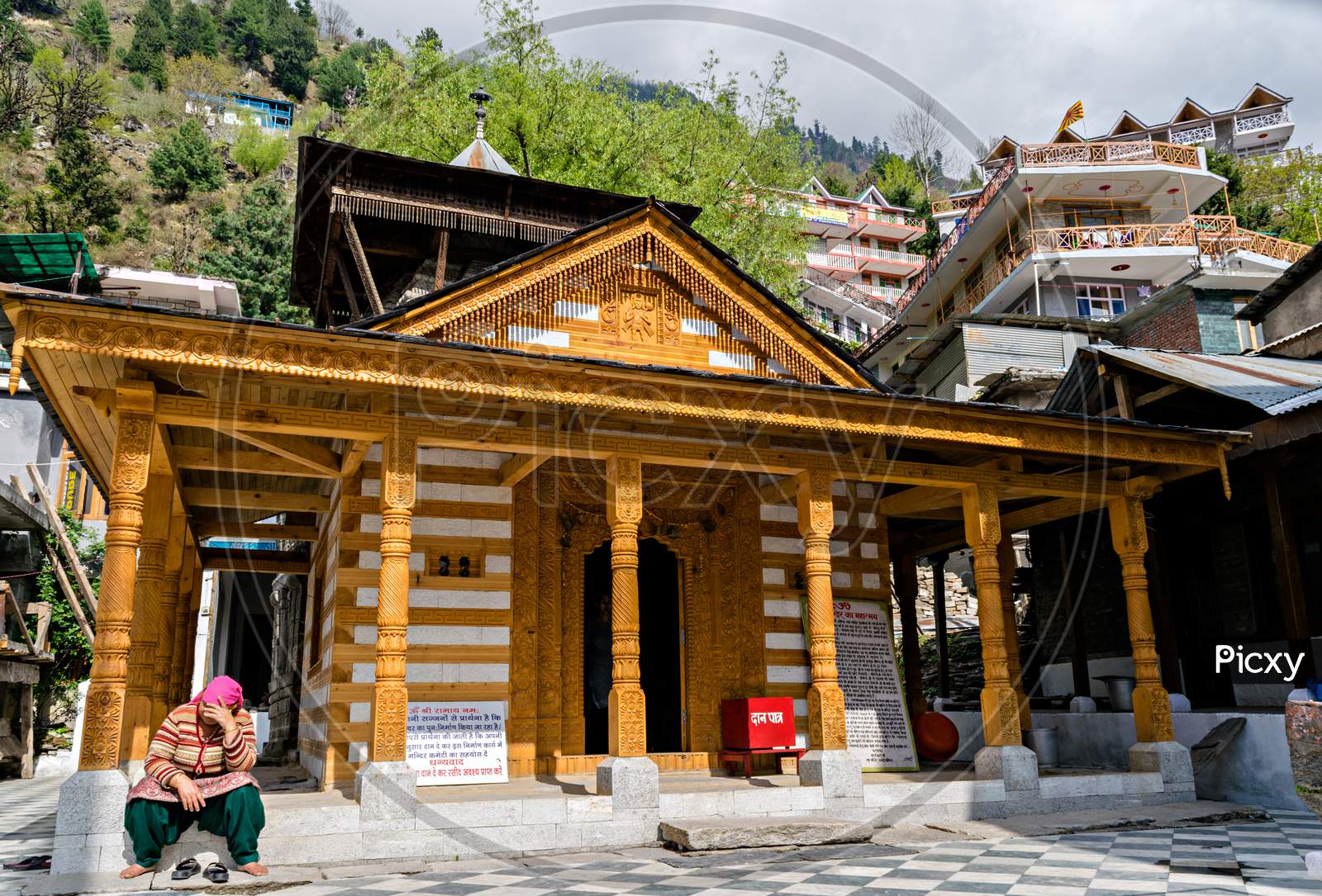 A Lady Sitting In Sunlight In Front Of Vashistha Temple Famous For Hot Water Springs In Manali, Himachal Pradesh, India.