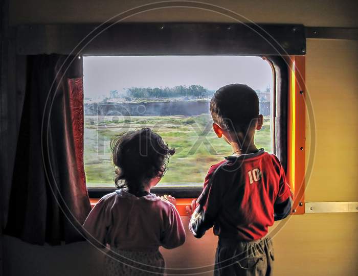 Maharashtra, India-October 15H, 2009:Two Young Children Curiously Watching Outside Through A Train Window.