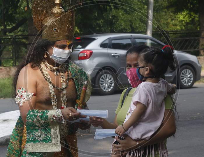 A man wears mask  dressed as Hindu Lord Krishna distributes masks to people at a road during Janmashtami celebrations, in Chandigarh August 11, 2020