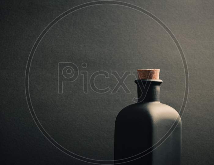 A Close Up Of A Black Ceramic Bottle With A Dark Background