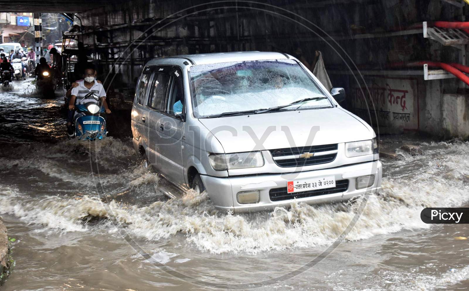 People drive on the road during heavy rains in Prayagraj, August 12, 2020.