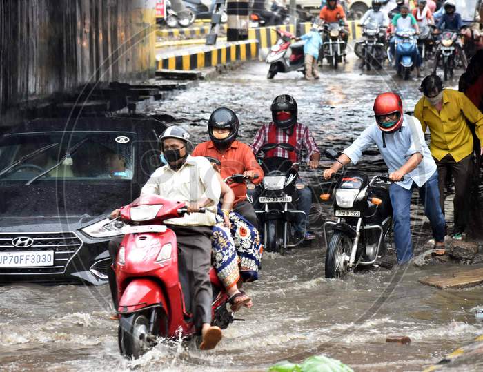 People wade through water on the road during heavy rains in Prayagraj, August 12, 2020.