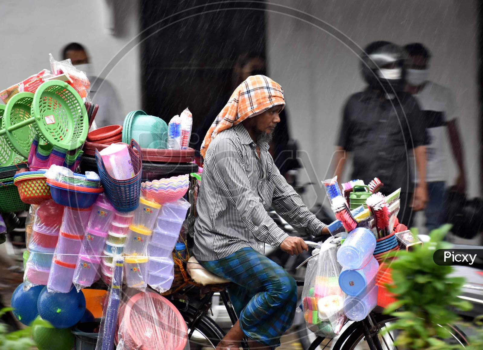 A vendor cycles on the road during heavy rains in Prayagraj, August 12, 2020.