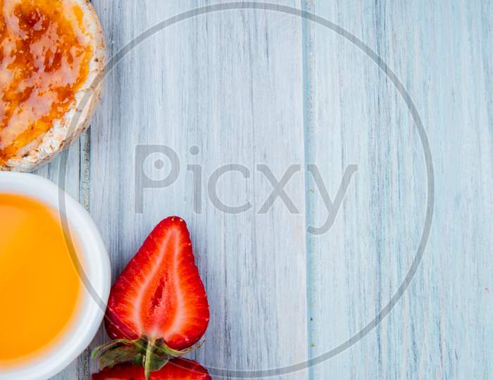 Top View Of Half Cut Strawberries With Oats Crispbread Peach Syrup Cupcake Butter On Wooden Background With Copy Space