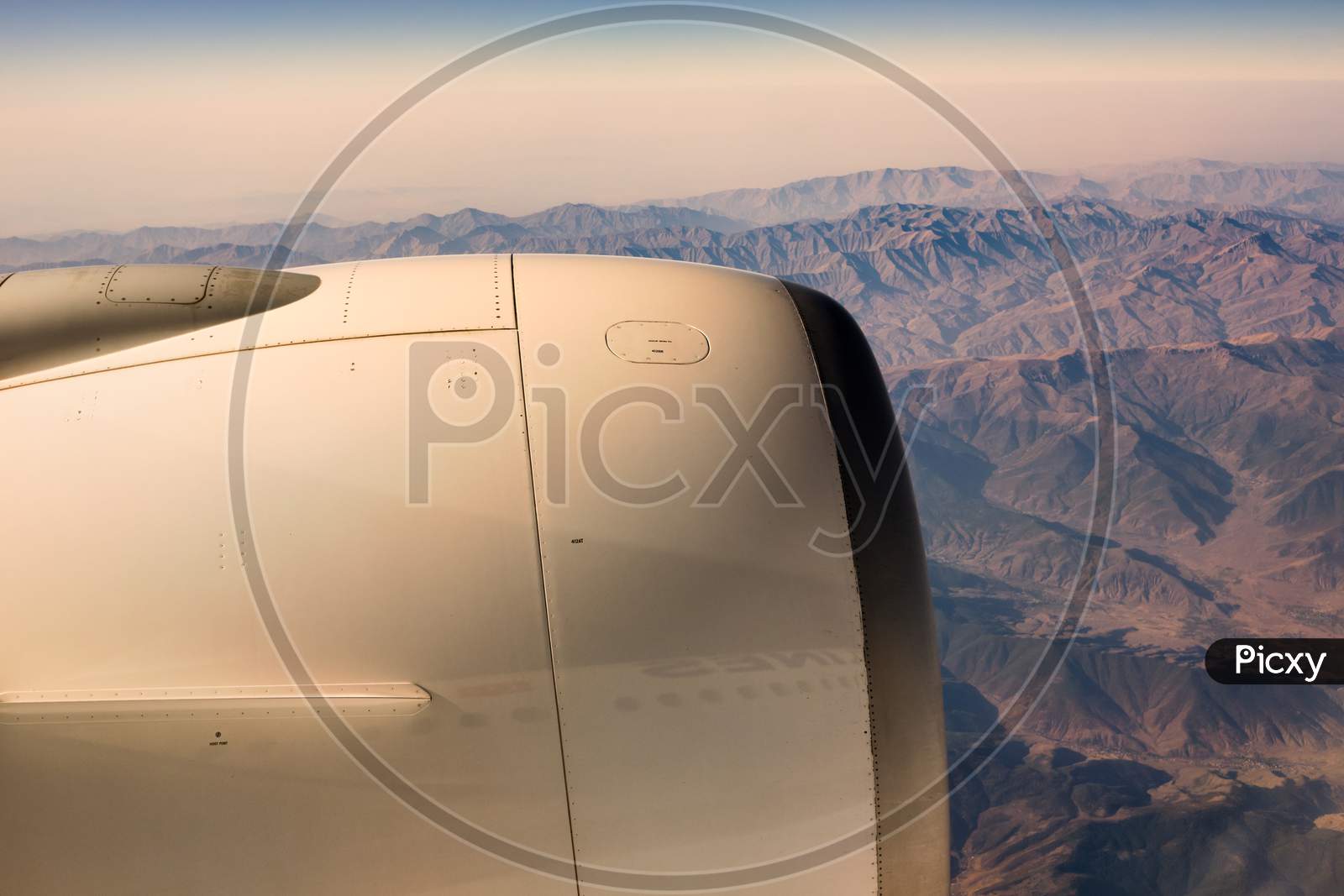 Areal View From The Window Of An Airplane Of Aircraft Engine And Rugged Mountainous Landscape
