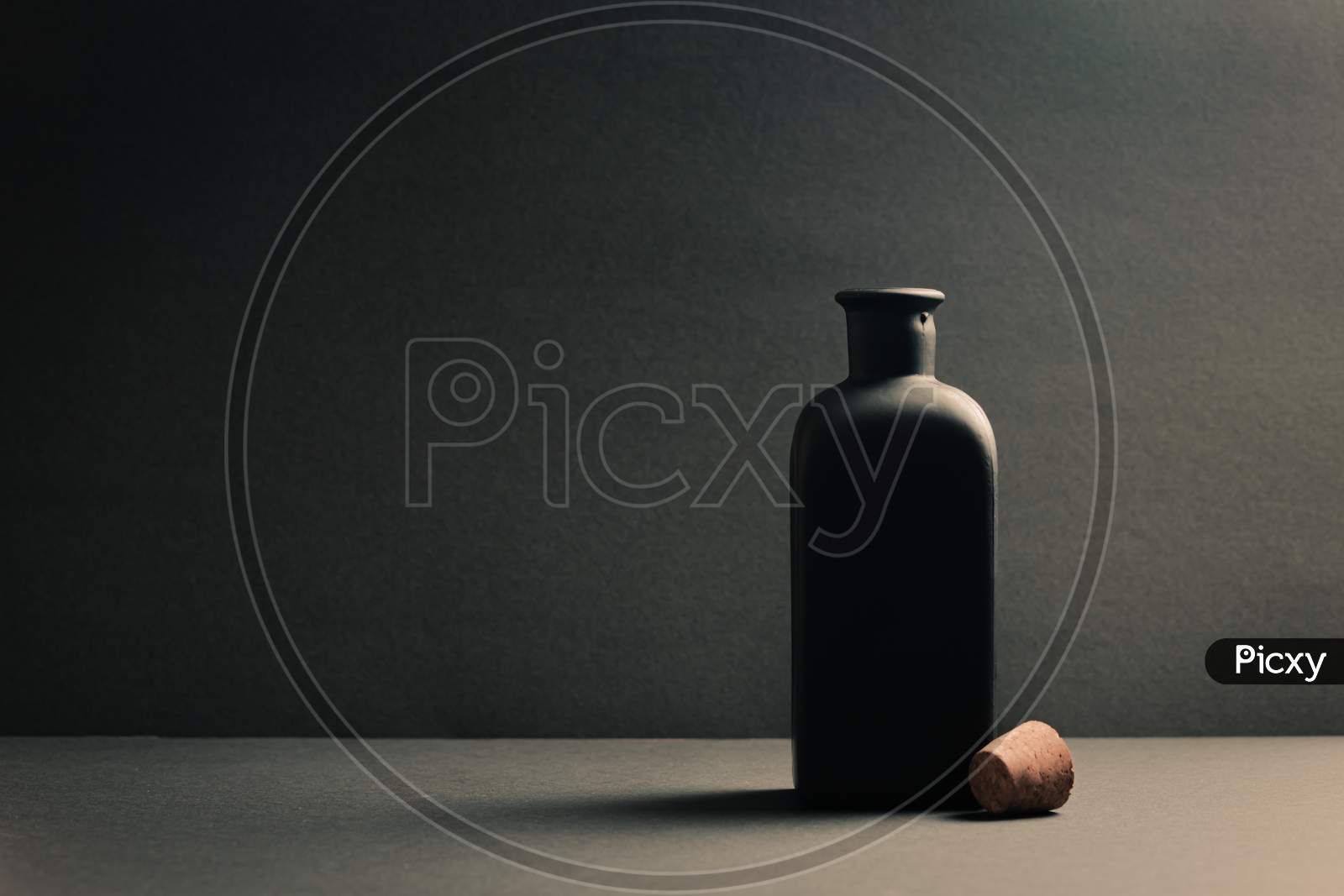 Single Black Ceramic Bottle With The Plug Off Over A Dark Background