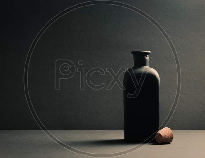 Single Black Ceramic Bottle With The Plug Off Over A Dark Background