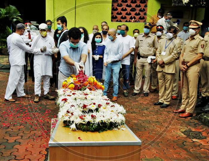 Son of deceased Air India pilot Deepak Sathe places flowers on his coffin during his funeral in Mumbai, India on August 11, 2020.