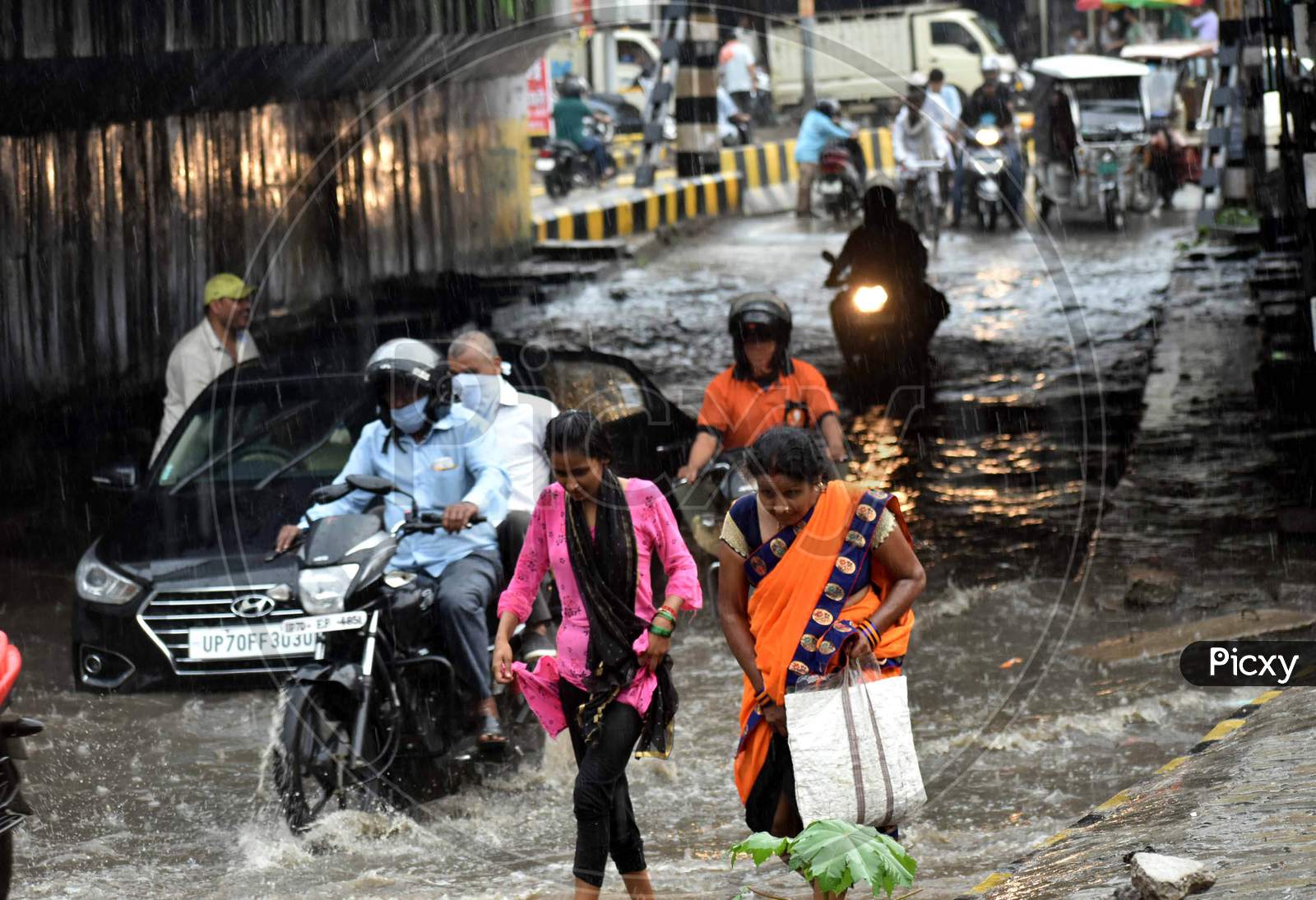 People wade through water on the road during heavy rains in Prayagraj, August 12, 2020.