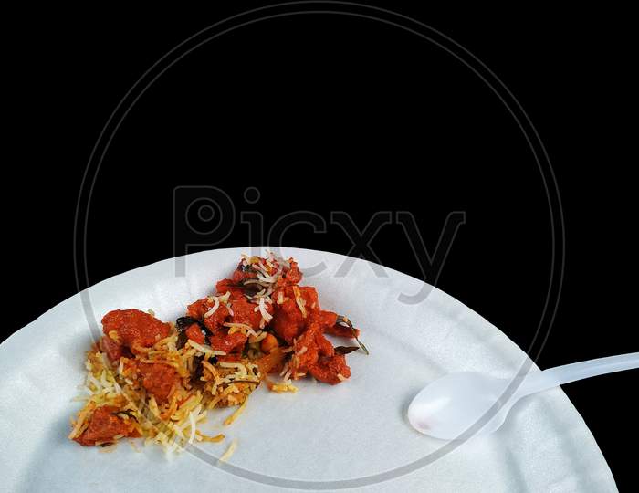 Top view of Delicious Indian Chicken Biryani/ savory rice dish that is loaded with spicy marinated chicken and flavoured saffron rice/ garnished with indian spices and herbs with black background.