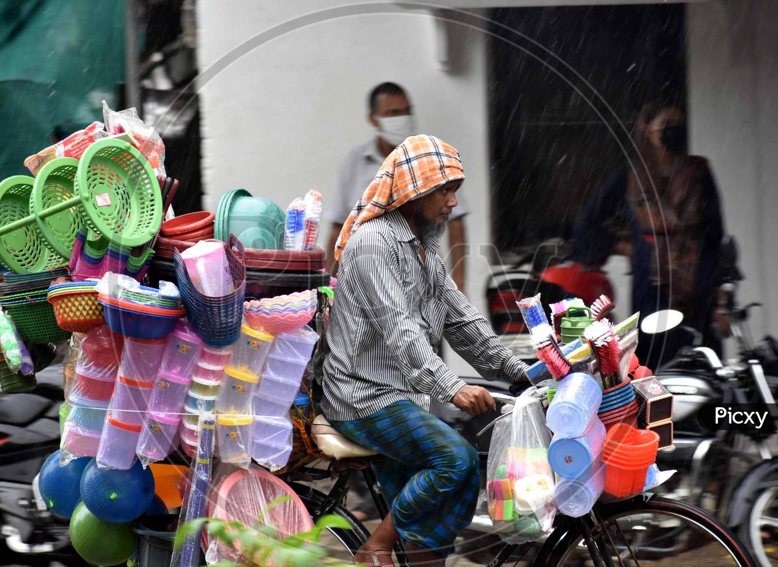 A vendor cycles on the road during heavy rain in Prayagraj, August 12, 2020.