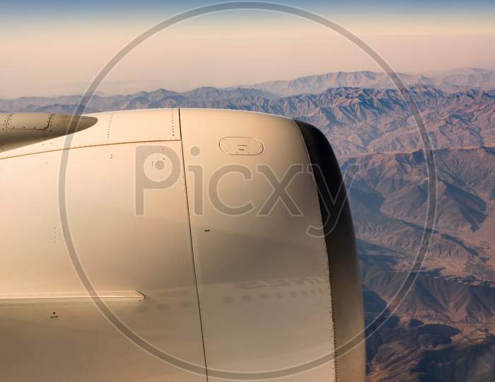 Areal View From The Window Of An Airplane Of Aircraft Engine And Rugged Mountainous Landscape
