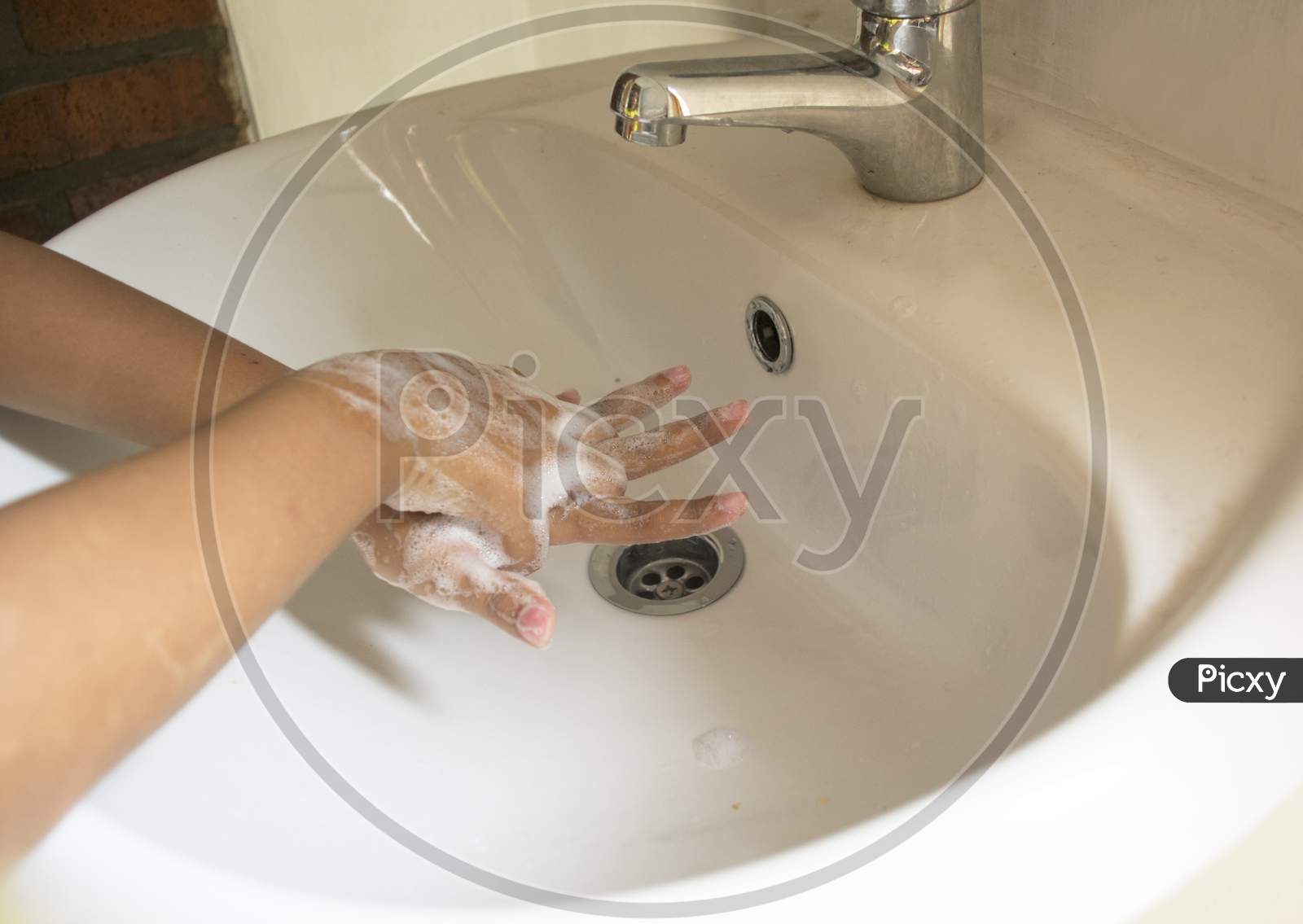 Washing Hands With Foamy Hand Soap Rubbing And Grasping Between The Fingers Of The Back Of The Hand Over The Sink