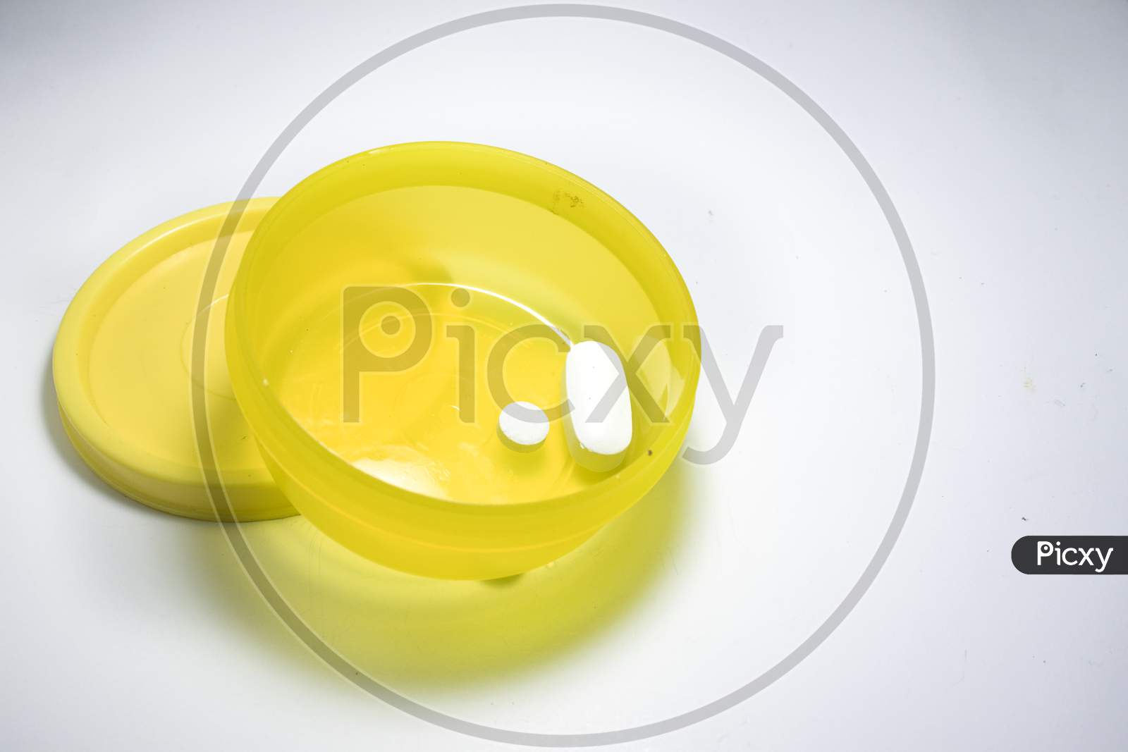 White Pill In A Yellow Small Yellow Container.