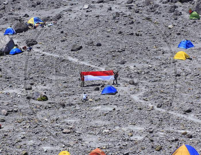 Climber stretches the Indonesian flag red and white in the last camping spot on Mount Merapi