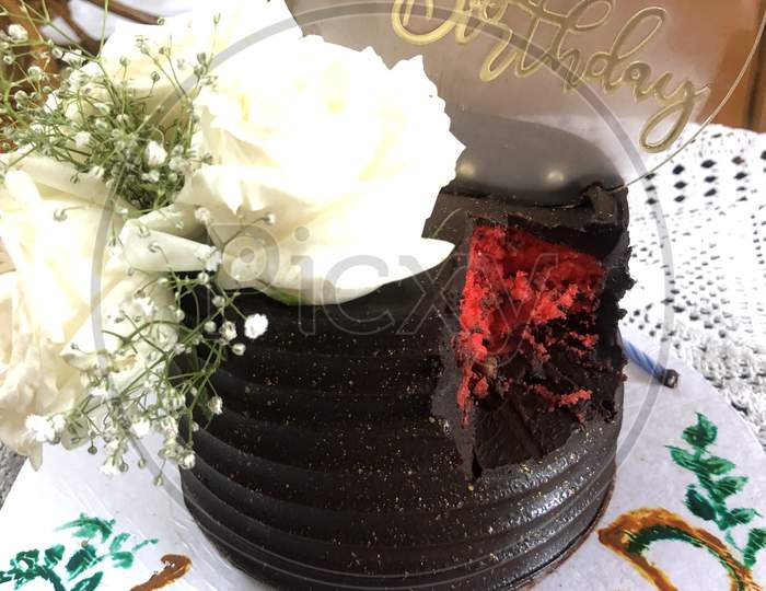 A beautiful red velvet and chocolate cake for birthday to husband from wife decorated with white roses