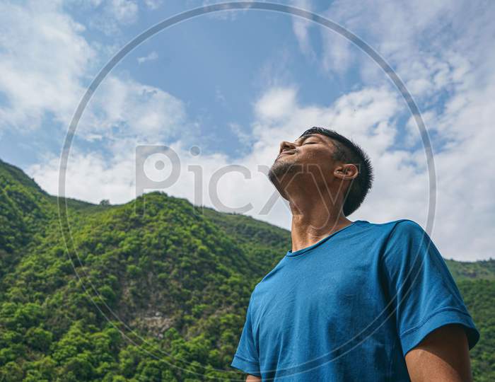 Young Indian Boy Standing In The Edge Of The Balcony, Enjoying The Scenic View Of The Green Mountains.