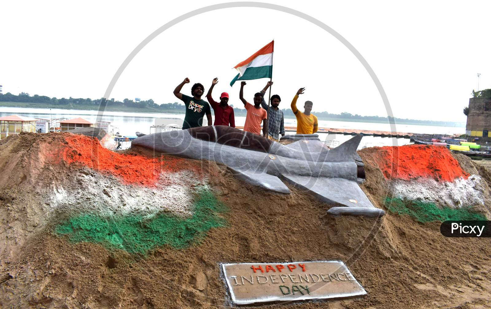 Students make sand art of tri-colored national flags ahead of Independence day celebration on the river bank of Yamuna in Prayagraj, August 14, 2020.